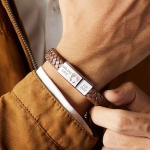 Puede incluir: Pulsera trenzada de cuero marr&oacute;n con una placa plateada grabada con "HARLOW 2.10.22" y una huella de pie, y otra placa plateada grabada con "6LB 15OZ".