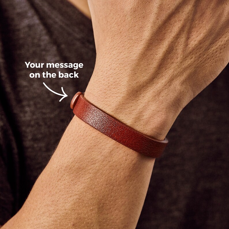 May include: A brown leather bracelet with a silver buckle. The bracelet is worn on a person's wrist. The text "Your message on the back" is written on the image.