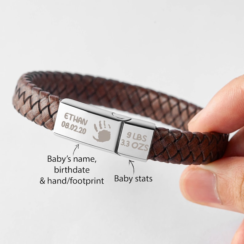 Puede incluir: Pulsera trenzada de cuero marr&oacute;n con un cierre plateado grabado con "ETHAN 08.02.20" y una huella de mano. El cierre tambi&eacute;n est&aacute; grabado con "9 LBS 3.3 OZS".