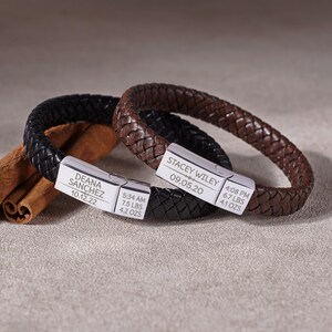 Puede incluir: Dos pulseras de cuero trenzado, una negra y otra marr&oacute;n, con cierres plateados. La pulsera negra est&aacute; grabada con "DEANA SANCHEZ" y "10.12.22", junto con el peso y la hora. La pulsera marr&oacute;n est&aacute; grabada con "STACEY WILEY" y "09.05.20", con el peso y la hora.