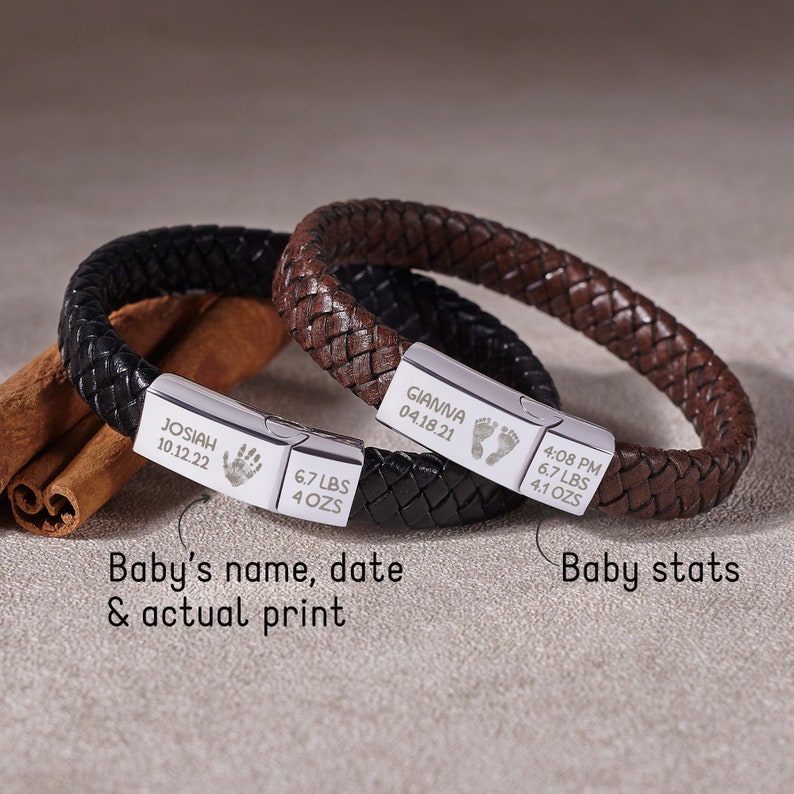 Puede incluir: Dos pulseras de cuero con placas de plata grabadas. Una pulsera es de cuero marr&oacute;n y la otra de cuero negro. Las placas incluyen los nombres "Gianna" y "Josiah", las fechas y las huellas de los pies. Las placas tambi&eacute;n incluyen el peso del beb&eacute; y la hora de nacimiento.