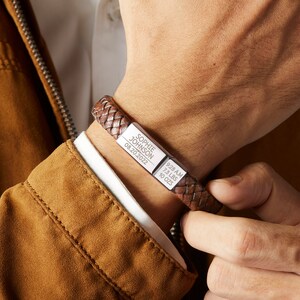 Puede incluir: Pulsera de cuero trenzado marr&oacute;n con una placa rectangular plateada. La placa est&aacute; grabada con el nombre "Sophie Johnson", la fecha "08.20.2022", la hora "9:28 AM", el peso "3,3 kg" y "283 g".