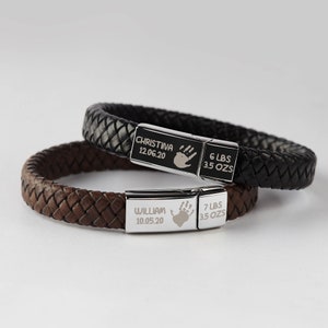 Puede incluir: Dos pulseras de cuero con placas de acero inoxidable grabadas. La pulsera superior es negra y la inferior es marr&oacute;n. Las placas tienen los nombres Christina y William, las fechas de nacimiento, las huellas de las manos y los pesos y las onzas.