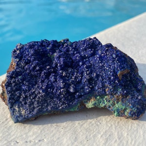 May include: A rough, blue and green azurite mineral specimen. The azurite has a deep blue color and a rough, textured surface.