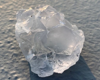 May include: A large, clear, white crystal with many facets. The crystal is irregularly shaped and has a rough, natural texture.