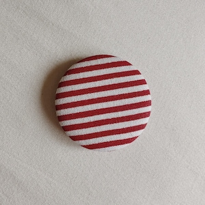 May include: A red and white striped fabric button.