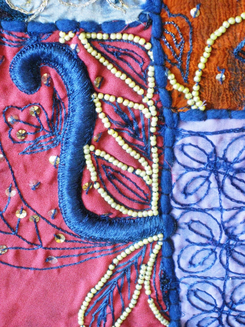 Peut inclure: Gros plan sur un patchwork de tissu color&eacute; avec des broderies bleues, rouges et blanches. Le tissu est d&eacute;cor&eacute; de perles et de paillettes.