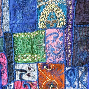 May include: A patchwork quilt with a variety of colors and patterns, including blue, green, pink, and orange. The quilt is made of different fabrics and textures, and features intricate embroidery and beading.