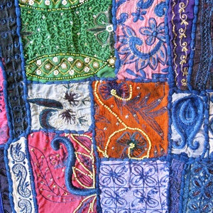 Peut inclure: Une courtepointe color&eacute;e en patchwork avec des broderies et des perles complexes. La courtepointe est compos&eacute;e de diff&eacute;rents tissus dans des tons de bleu, vert, rouge, orange et rose. La courtepointe est un bel exemple de l'artisanat indien traditionnel.