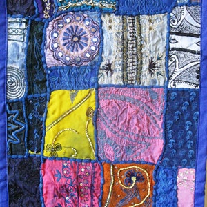 Peut inclure: Une courtepointe patchwork avec une vari&eacute;t&eacute; de couleurs et de motifs, notamment du bleu, du rose, du jaune et de l'orange. La courtepointe est faite de diff&eacute;rents tissus et textures, et elle a un style unique et &eacute;clectique.