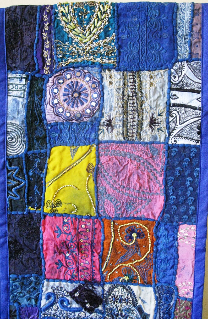 Peut inclure: Une courtepointe patchwork avec une vari&eacute;t&eacute; de couleurs et de motifs, notamment du bleu, du rose, du jaune et de l'orange. La courtepointe est faite de diff&eacute;rents tissus et textures, et elle a un style unique et &eacute;clectique.