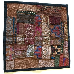 May include: A patchwork quilt with a variety of colors and textures, including brown, red, blue, and green. The quilt is made of different fabrics and is decorated with embroidery and beads.