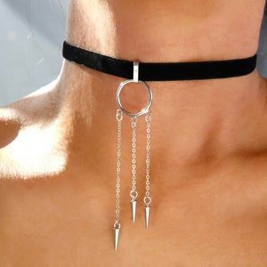 May include: A black velvet choker necklace with a silver circle pendant and three silver chains with pointed ends.