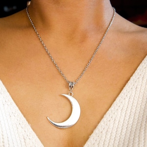 May include: A silver chain necklace with a crescent moon pendant.