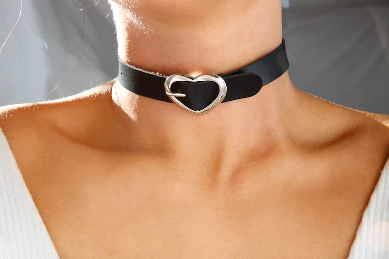 Pu&ograve; includere: Un colletto nero in pelle con una fibbia a forma di cuore argentata.
