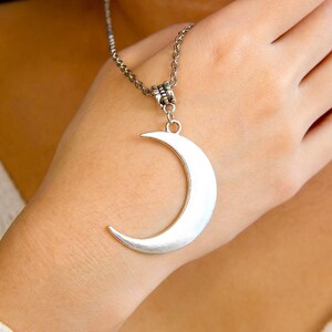 May include: A silver crescent moon pendant necklace on a silver chain.