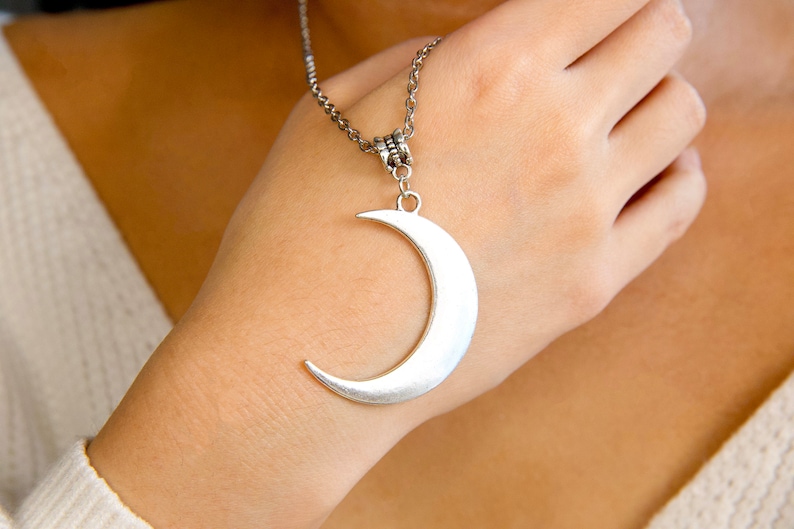 May include: A silver crescent moon pendant necklace on a silver chain.