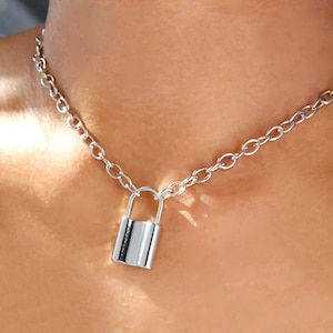 May include: A silver chain necklace with a padlock pendant.
