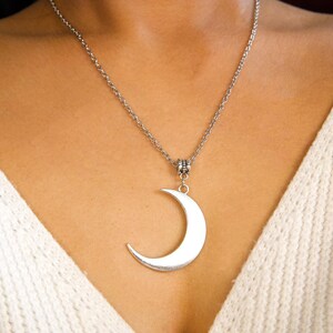 May include: A silver chain necklace with a crescent moon pendant.