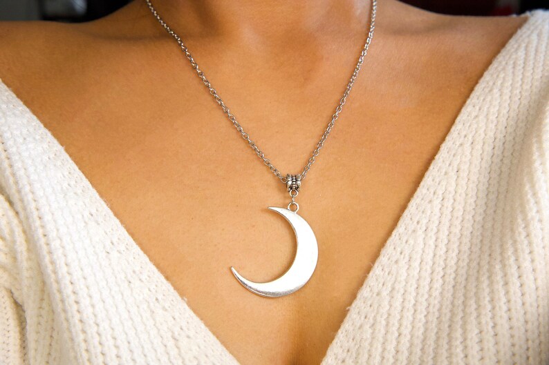 May include: A silver chain necklace with a crescent moon pendant.
