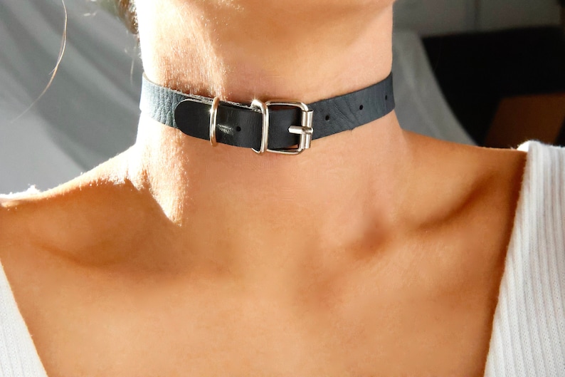 Pu&ograve; includere: Un choker in pelle nera con una fibbia argentata.
