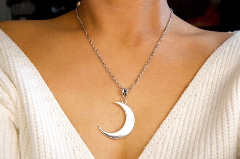 May include: A silver chain necklace with a crescent moon pendant.