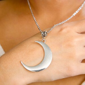 May include: A silver crescent moon pendant necklace. The pendant is large and hangs from a delicate silver chain.