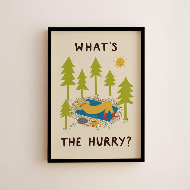 May include: A framed wall art print on a cream background featuring the text WHAT'S THE HURRY? in brown. The illustration shows a yellow figure resting on a blue blanket in a forest of green pine trees with a yellow sun and a small basket.