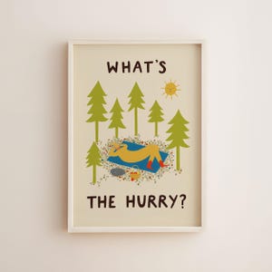 May include: A framed wall art print on a cream background featuring the text WHAT'S THE HURRY? in dark brown. The illustration shows a yellow figure lying on a blue blanket in a green pine forest with a yellow sun and a small basket of fruit.