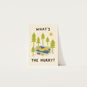 May include: A cream-colored greeting card featuring a cartoon illustration of a yellow figure relaxing on a blue blanket under green pine trees. The text WHAT'S THE HURRY? is printed in brown, with a small yellow sun and a basket nearby.