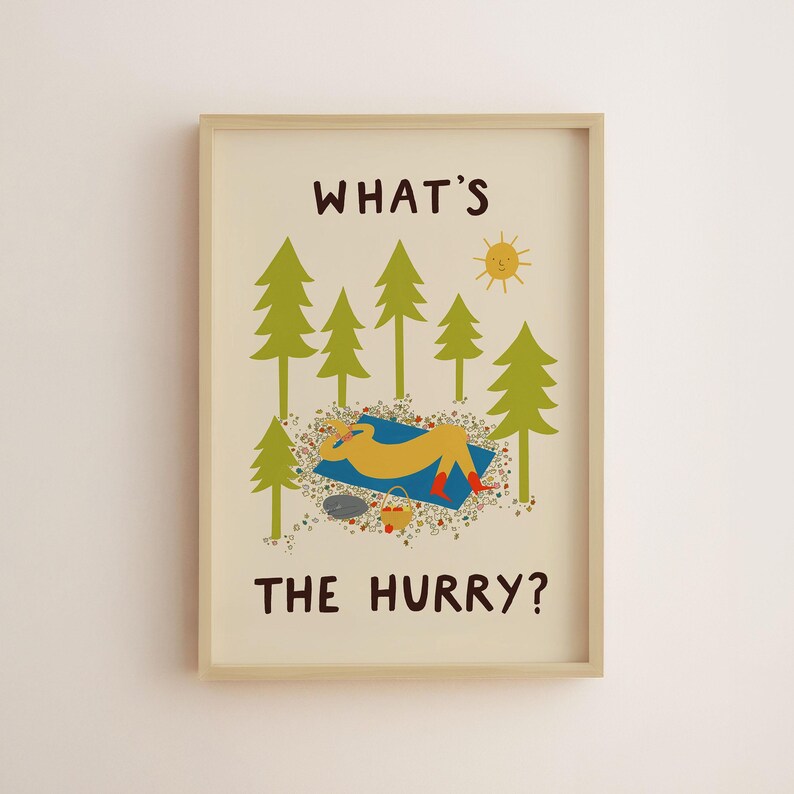 May include: A framed wall art print on a cream background featuring green pine trees, a yellow sun, and a figure resting on a blue blanket. The text reads WHAT'S THE HURRY? The illustration includes a small basket and scattered colorful floral details.