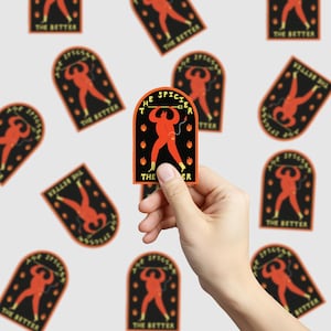 Może przedstawiać: Naklejka trzymana w dłoni, przedstawiająca czerwoną postać diabła z widłami, otoczoną płomieniami, z napisem "THE SPICIER THE BETTER" w czarnym łuku. Dodatkowe naklejki z tym samym wzorem są rozrzucone.
