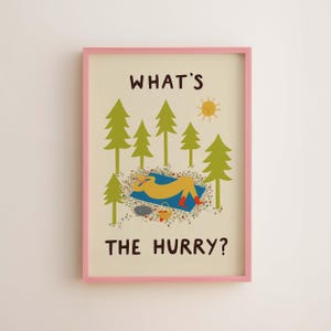 May include: A framed wall art print with a light cream background and a pink frame. The illustration features green pine trees, a yellow sun, and a figure resting on a blue blanket with red boots. The text reads WHAT'S THE HURRY? in brown.