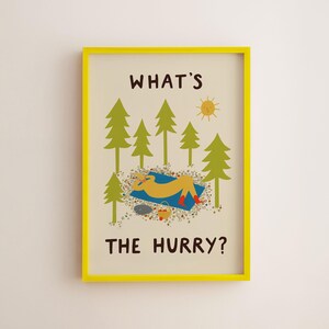 May include: A framed wall art print with a bright yellow frame. The illustration features green pine trees, a yellow sun, and a figure resting on a blue blanket. The text reads WHAT'S THE HURRY? in dark brown letters against a cream background.