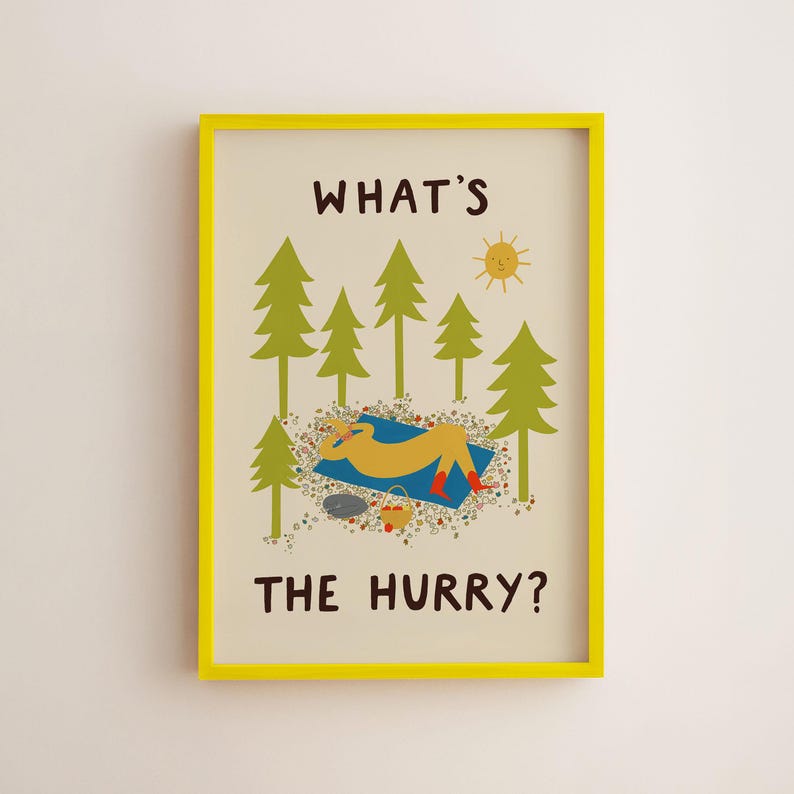 May include: A framed wall art print with a bright yellow frame. The illustration features green pine trees, a yellow sun, and a figure resting on a blue blanket. The text reads WHAT'S THE HURRY? in dark brown letters against a cream background.