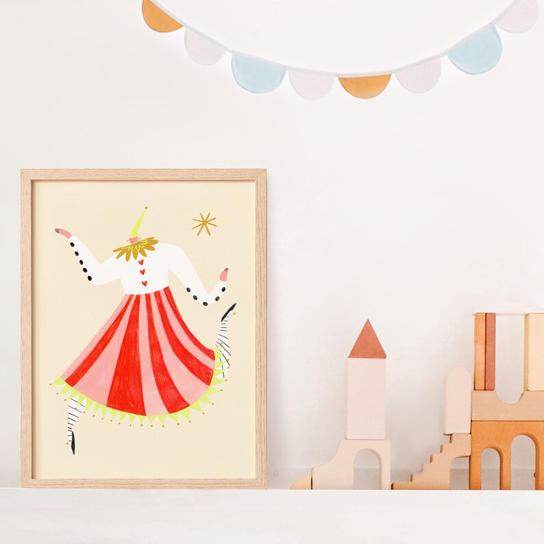 May include: A framed illustration of a stylized figure wearing a red and white striped skirt, a white shirt with black polka dots, and a yellow hat. The figure is dancing with one arm raised and the other arm extended to the side. The background is a light yellow.