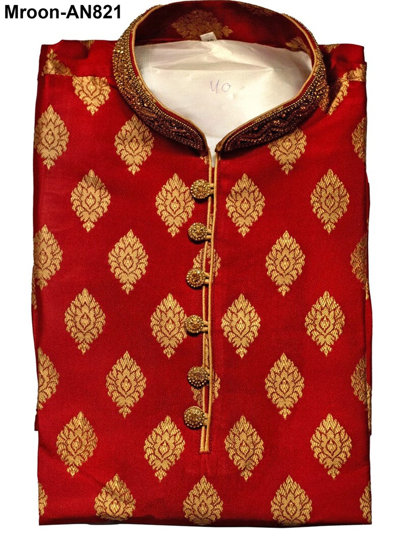 May include: A folded red kurta with a gold floral pattern. The collar and button placket are trimmed with gold beading and a gold border. The kurta has gold buttons and a mandarin collar. The text "Mroon-AN821" is in the top left corner.