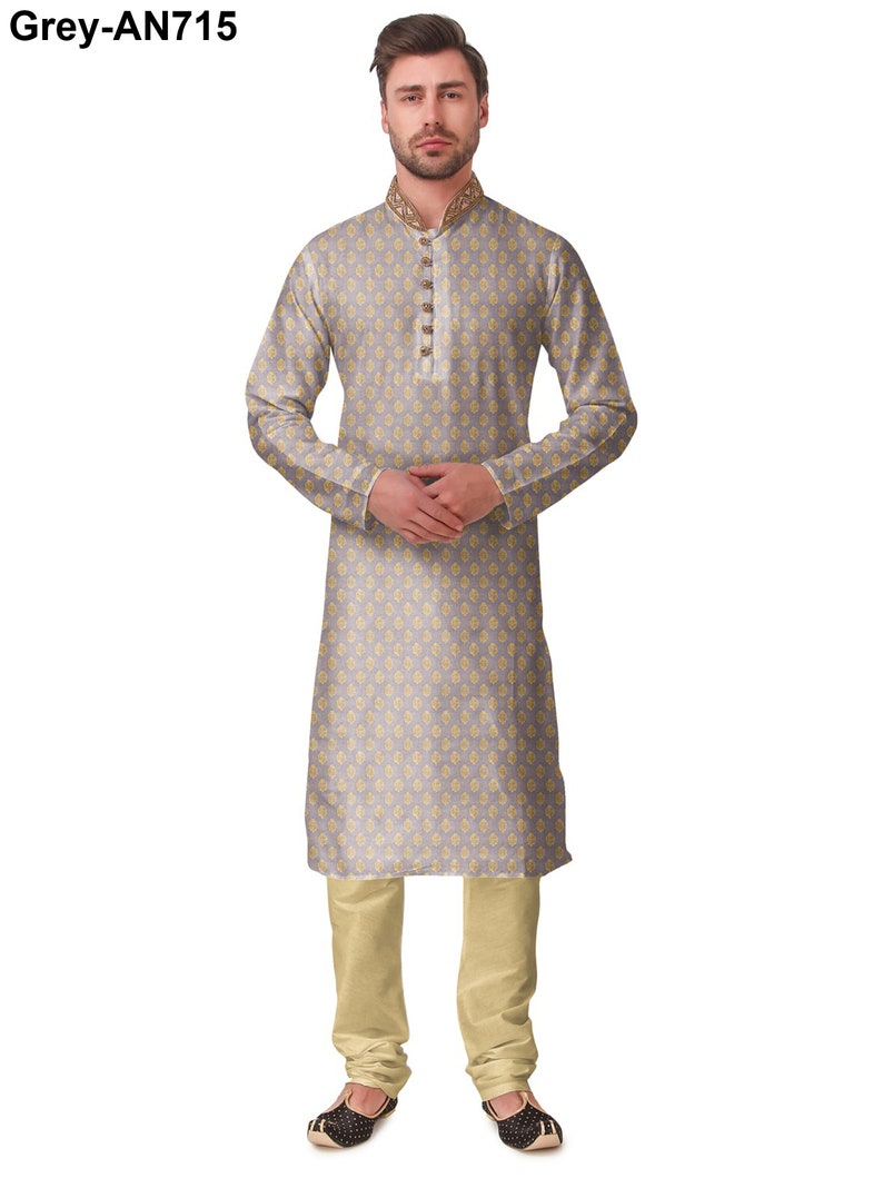 May include: A light grey kurta pajama set with a floral pattern. The kurta features a mandarin collar with gold embroidery and gold buttons. The matching pajama pants are a light beige color. The outfit is completed with black and gold embroidered shoes. The text "Grey-AN715" is in the top left corner.