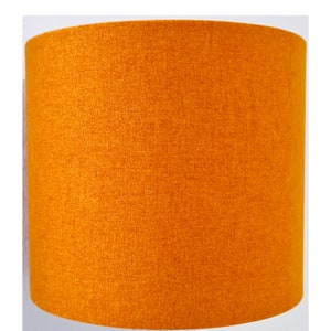 May include: A bright orange lampshade made of a textured fabric.