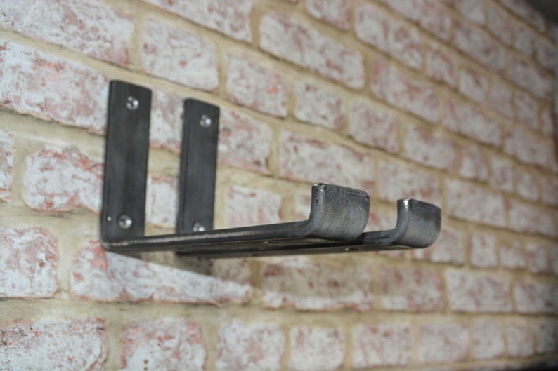 May include: A dark gray metal shelf with two vertical supports and a horizontal shelf, mounted on a brick wall. The shelf has a rustic, industrial design, with visible rivets. The brick wall is a mix of red, white, and tan bricks.
