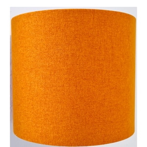 May include: A bright orange lampshade made of a textured fabric.