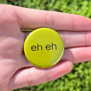 May include: A yellow button with the text "eh eh" printed in black.