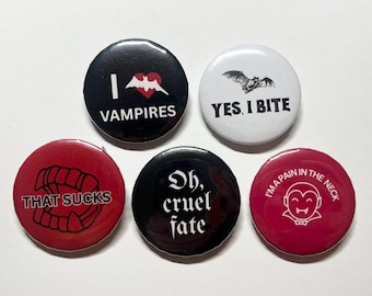 May include: A collection of five round buttons with vampire-themed designs. The buttons feature phrases like "I Vampires", "Yes, I Bite", and "That Sucks", along with vampire-related graphics in black, white, and red.