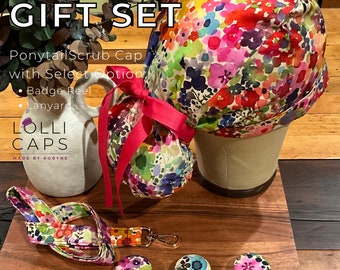 May include: A gift set for healthcare workers includes a floral patterned scrub cap with a ponytail hole, a matching lanyard, and a badge reel. The set is made by Lolli Caps.