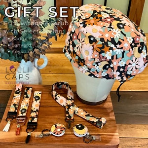 May include: A gift set for scrub caps featuring a floral print with a black background. The set includes a scrub cap, a lanyard, a badge reel, and a keychain. The text "GIFT SET" is at the top of the image. The text "Euro w/toggle Scrub Cap with Select Option: Badge Reel, Lanyard, Keychain" is below the image of the scrub cap. The text "LOLLI CAPS MADE BY ROBYNE" is at the bottom of the image.
