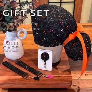 May include: A black scrub cap with a ghost and dot pattern, a matching black and white keychain, and a black badge reel with a ghost and dot pattern. The text "LOLLI CAPS MADE BY ROBYNE" is on the image. The text "lollicapsetsy.com" is on the image.
