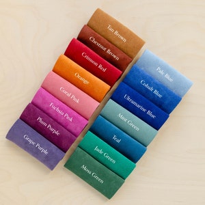 May include: A color palette of fabric swatches in various shades, including Tan Brown, Crimson Red, and Moss Green. Each swatch is labeled with its color name in white text. The arrangement showcases a range of hues, from warm oranges to cool blues.