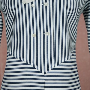 May include: A white and navy blue striped long-sleeved shirt with a double-breasted button closure.