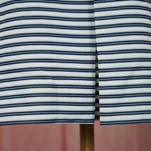 May include: White and navy blue striped fabric with a vertical seam down the centre.