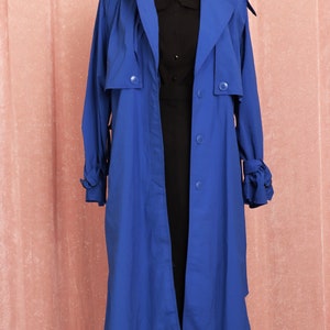 May include: A long, royal blue trench coat with a button closure and a tie at the cuffs.